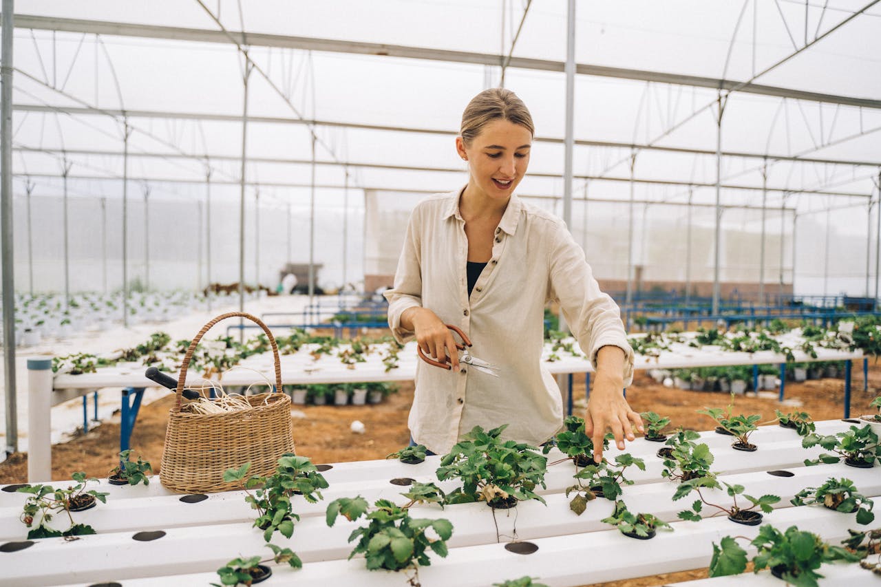 Smiling woman tending plants in a high-tech greenhouse, showcasing sustainable agriculture.